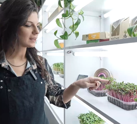 A MOĆNO founder showing microgreens on the farm shelves during the Better Land TV show