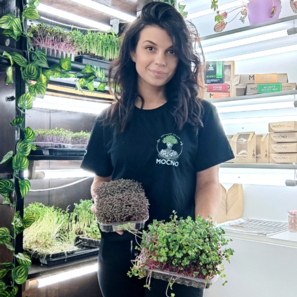 Milena Jovanović represents the richness of colors and textures of MOĆNO microgreens, holding pots with fresh shoots in a vertical farm.