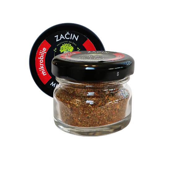 Central view of a small glass jar of MOĆNO dried microgreens spice with chilli. Clearly visible black label with red details and the recognizable MOĆNO logo on the lid.