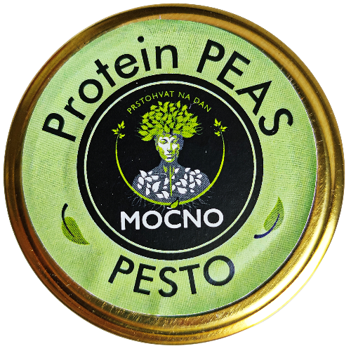Shot of the jar lid from above. The focus is on the circular light green label with the MOĆNO logo and the name "Protein Peas Pesto", which visually separates this flavor from other spreads in the assortment.