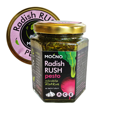 Central view of a hexagonal glass jar of Radish Rush pesto spread. Clearly visible black label with radish illustration and golden lid with a purple "Radish Rush" sticker.